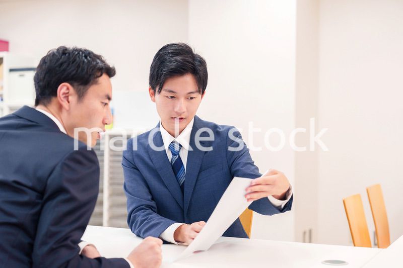 窓口で来客の対応をするビジネスマン