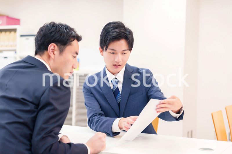 窓口で来客の対応をするビジネスマン