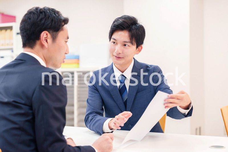 窓口で来客の対応をするビジネスマン