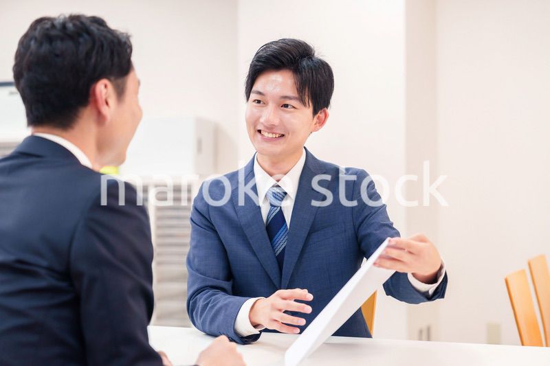 窓口で来客の対応をするビジネスマン