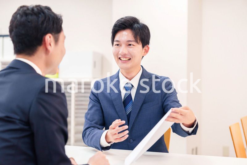 窓口で来客の対応をするビジネスマン