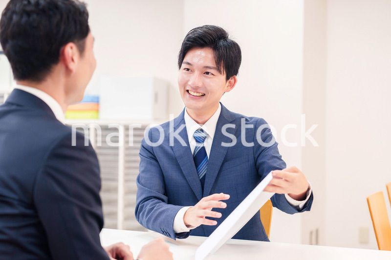 窓口で来客の対応をするビジネスマン