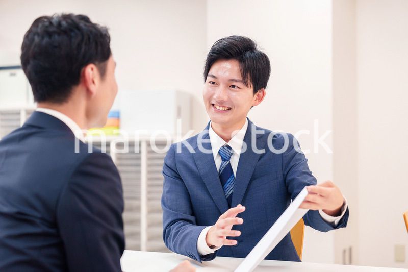 窓口で来客の対応をするビジネスマン