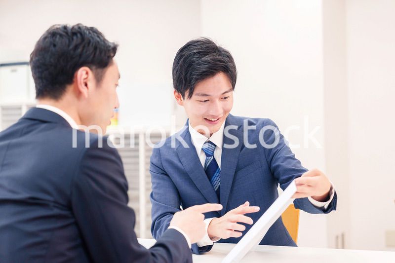 窓口で来客の対応をするビジネスマン