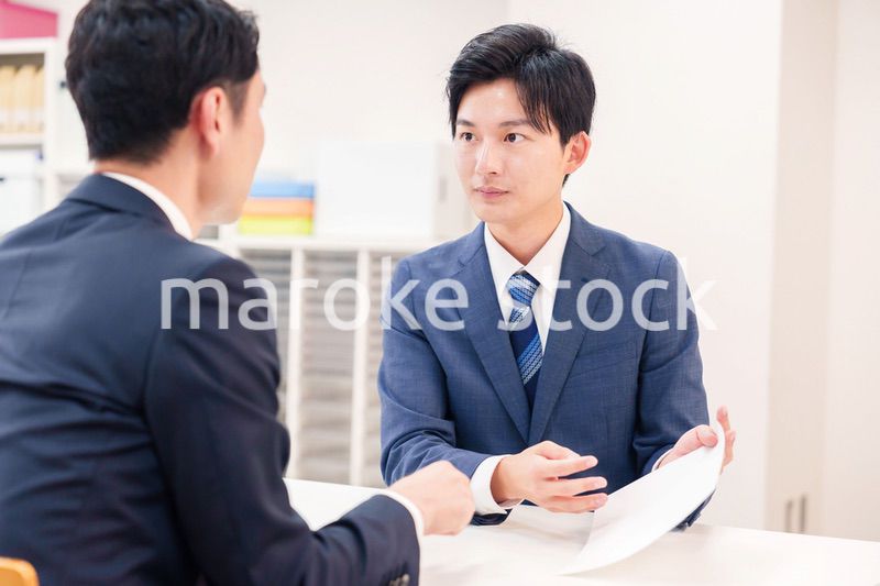 窓口で来客の対応をするビジネスマン