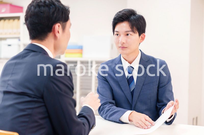 窓口で来客の対応をするビジネスマン