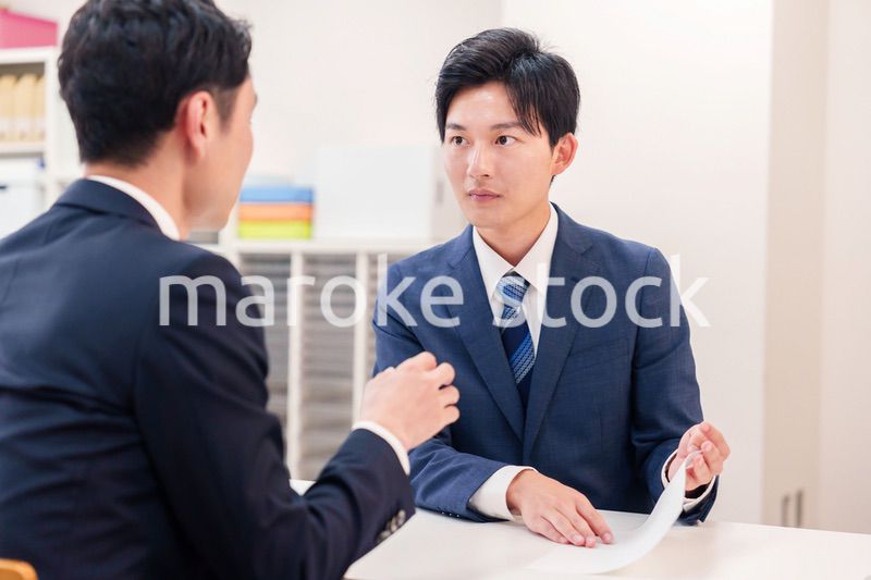 窓口で来客の対応をするビジネスマン