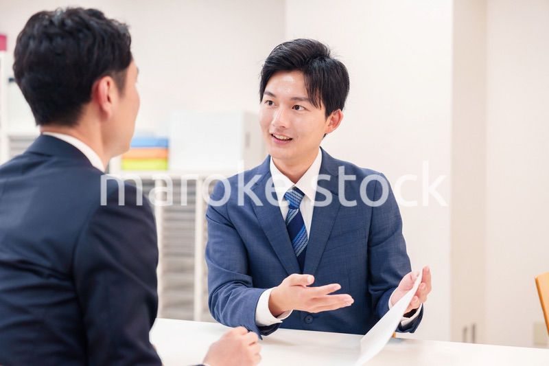 窓口で来客の対応をするビジネスマン