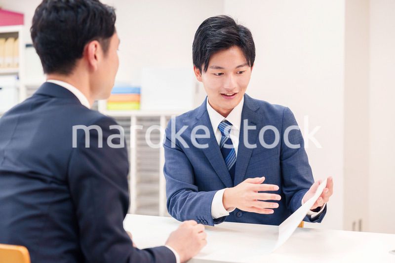 窓口で来客の対応をするビジネスマン