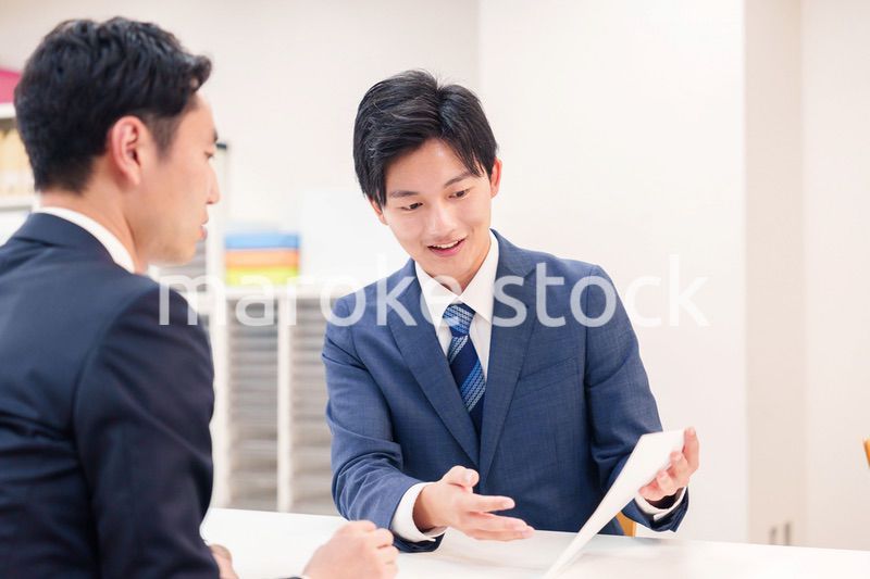 窓口で来客の対応をするビジネスマン