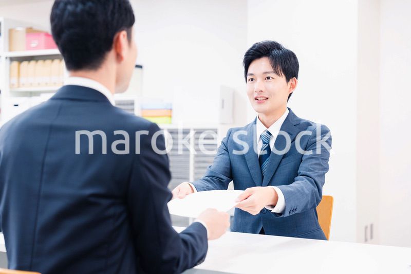 窓口で紙の書面の取り交わしをするビジネスマン