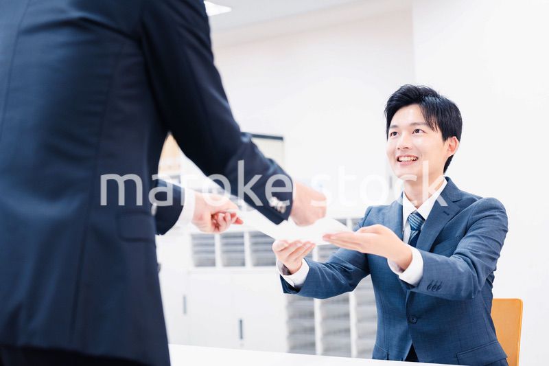窓口で紙の書面の取り交わしをするビジネスマン