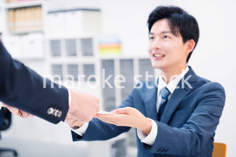 窓口で紙の書面の取り交わしをするビジネスマン