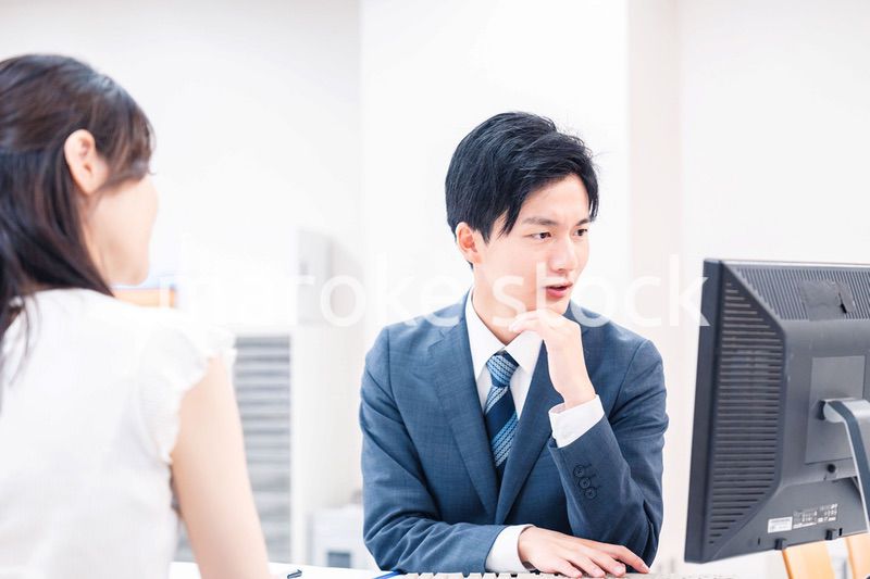 不動産会社のカウンターで相談をする若い女性