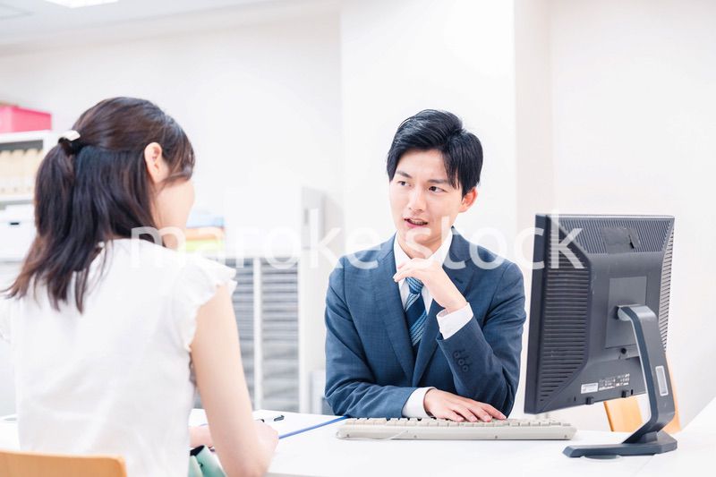 不動産会社のカウンターで相談をする若い女性