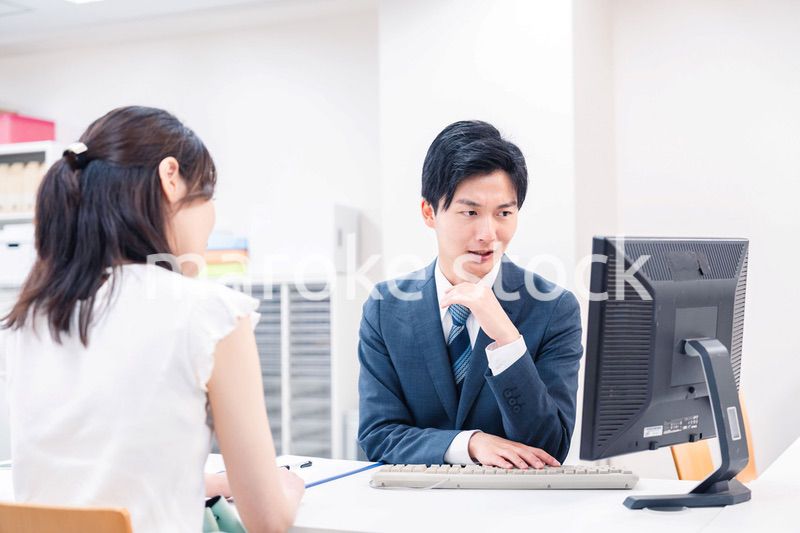 不動産会社のカウンターで相談をする若い女性