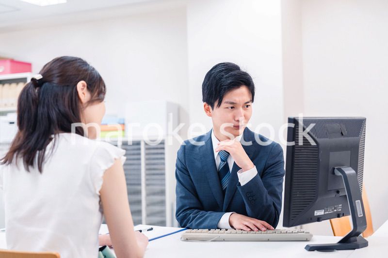 不動産会社のカウンターで相談をする若い女性