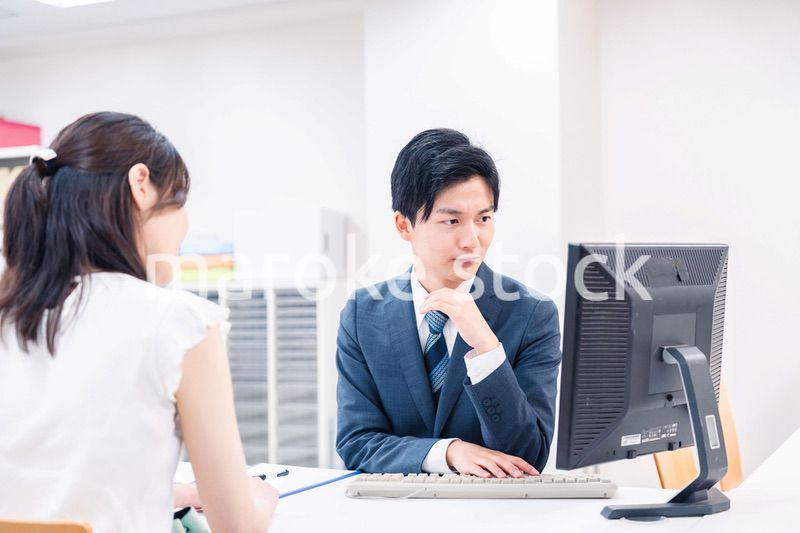 不動産会社のカウンターで相談をする若い女性