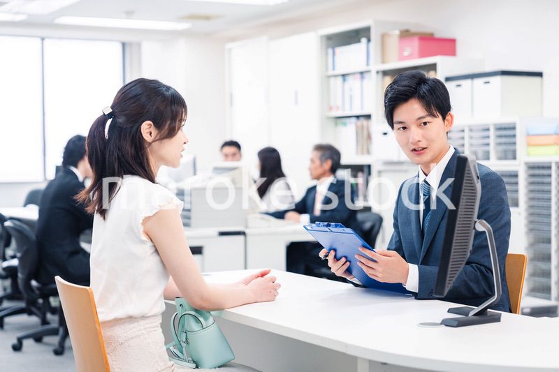 窓口で来客の対応をするビジネスパーソン