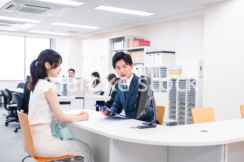窓口で来客の対応をするビジネスパーソン