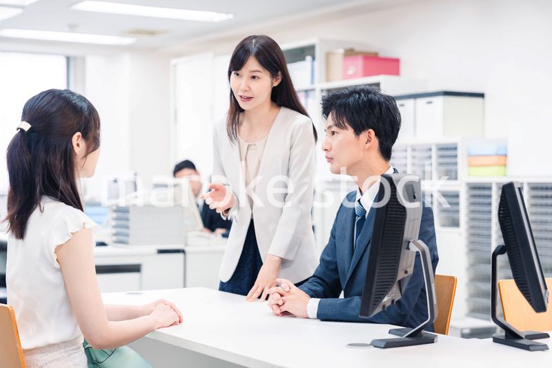 窓口で来客の対応をするビジネスパーソン