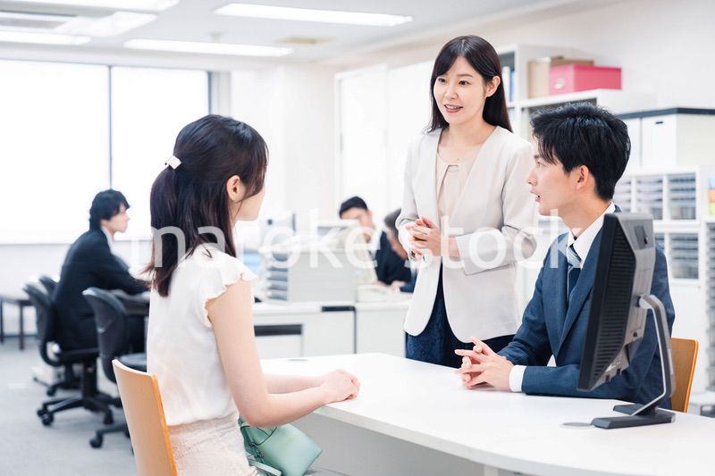 窓口で来客の対応をするビジネスパーソン