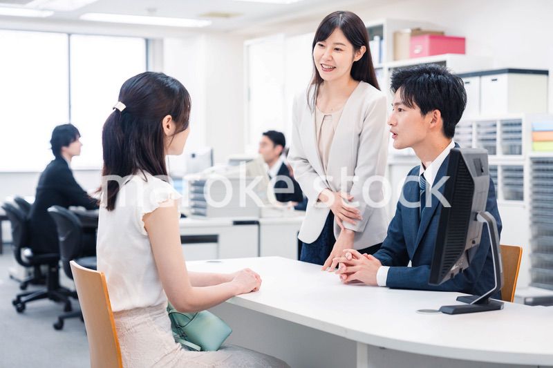 窓口で来客の対応をするビジネスパーソン