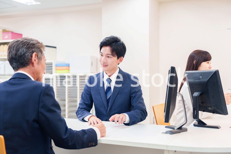 窓口で高齢者の来客の対応をする男性