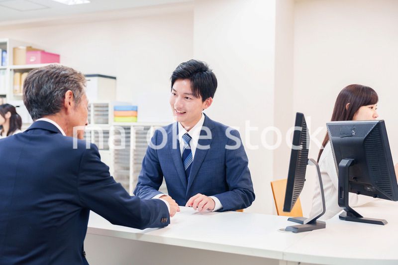 窓口で高齢者の来客の対応をする男性