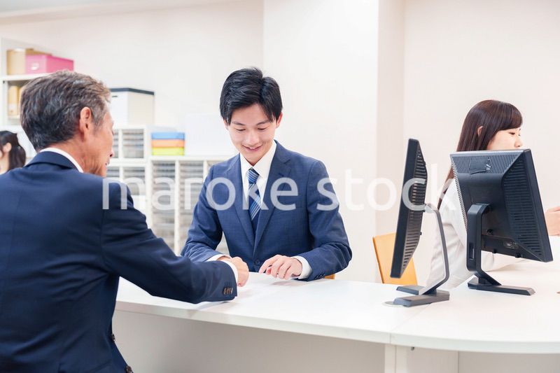 窓口で高齢者の来客の対応をする男性