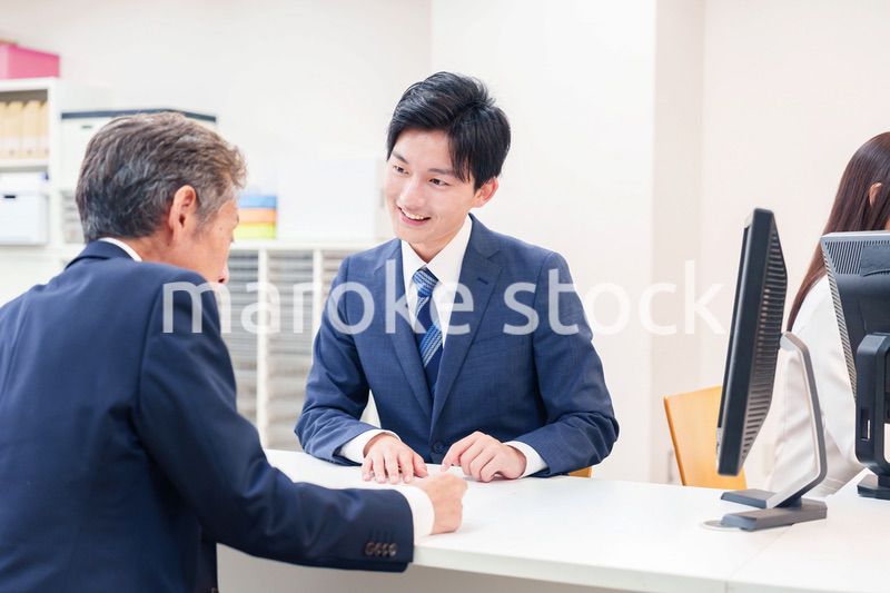 窓口で高齢者の来客の対応をする男性