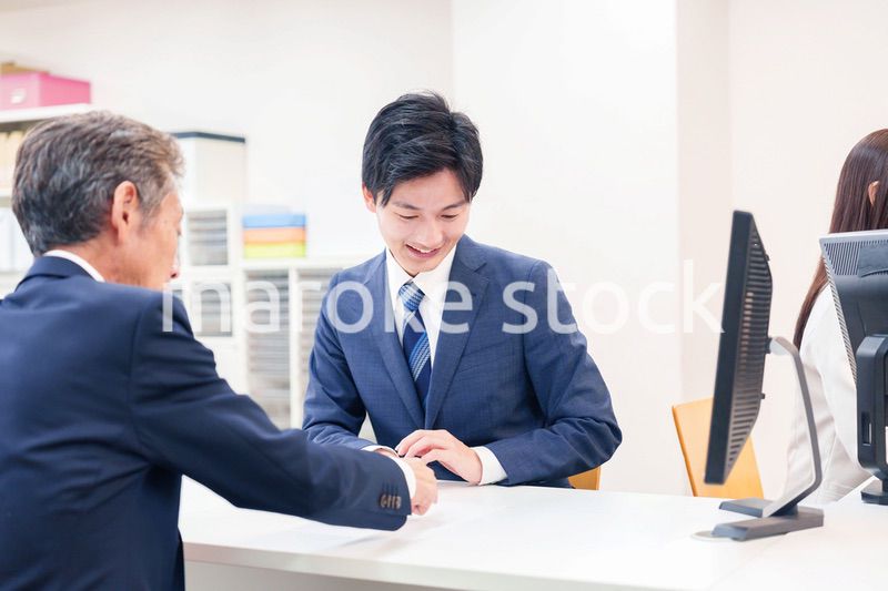 窓口で高齢者の来客の対応をする男性