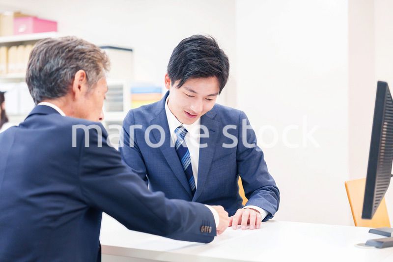 窓口で高齢者の来客の対応をする男性