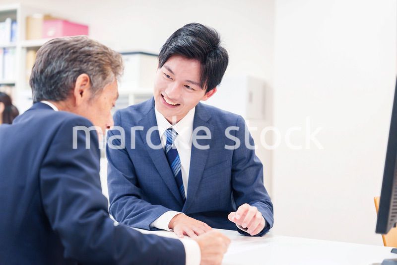 窓口で高齢者の来客の対応をする男性