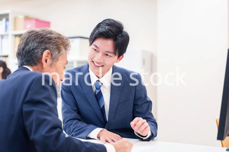 窓口で高齢者の来客の対応をする男性