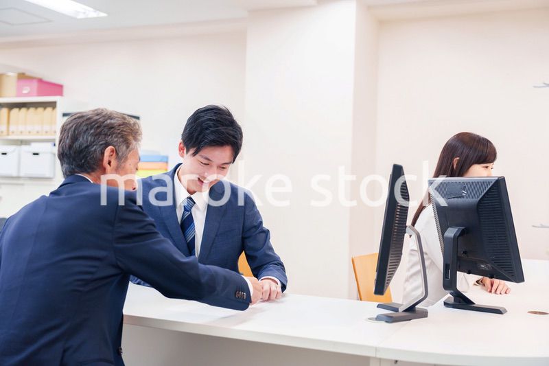 窓口で高齢者の来客の対応をする男性