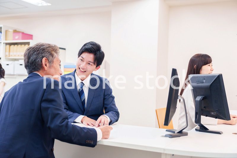 窓口で高齢者の来客の対応をする男性