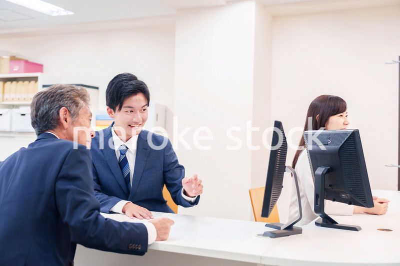 窓口で高齢者の来客の対応をする男性