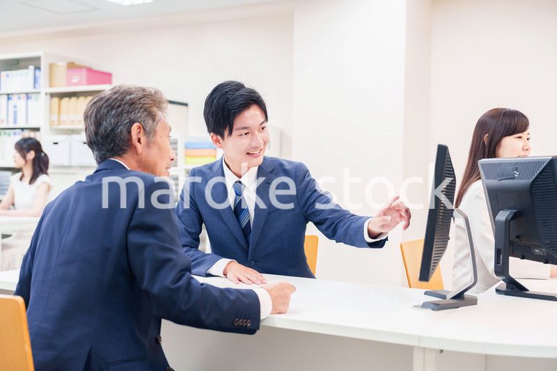 窓口で高齢者の来客の対応をする男性