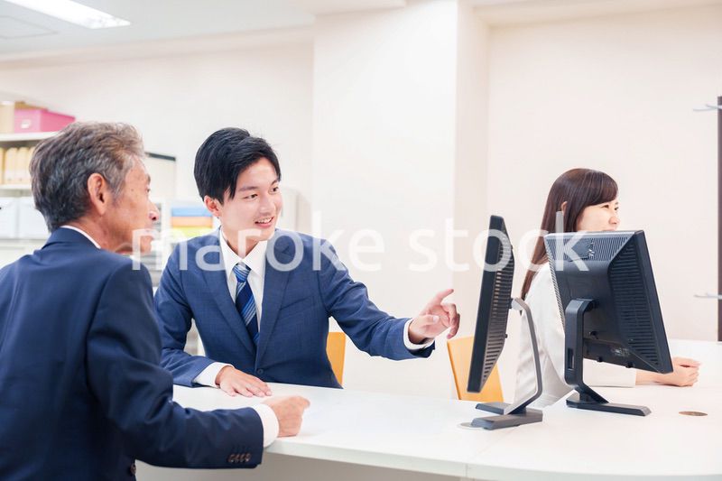 窓口で高齢者の来客の対応をする男性