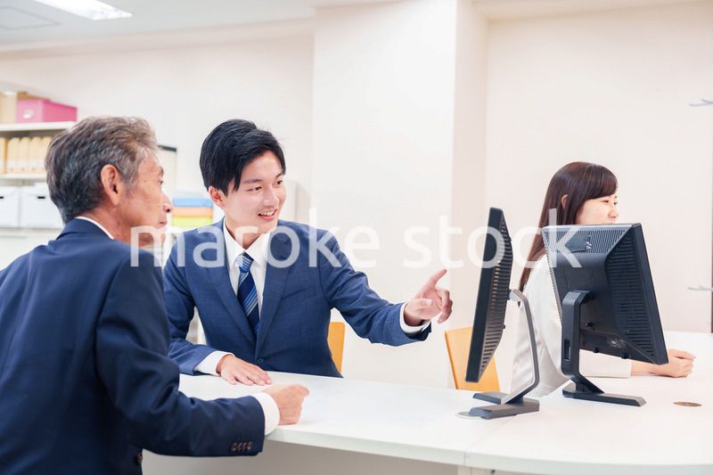 窓口で高齢者の来客の対応をする男性