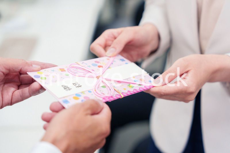 上司からお祝いを手渡されるビジネスウーマン