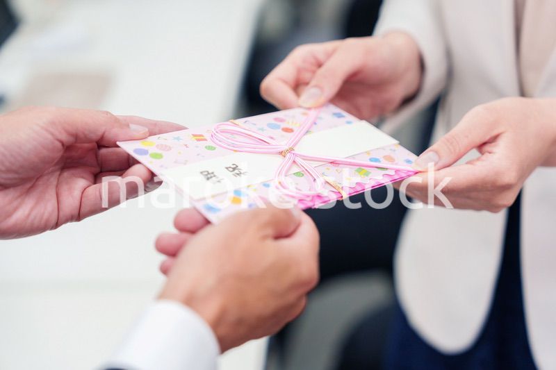 上司からお祝いを手渡されるビジネスウーマン