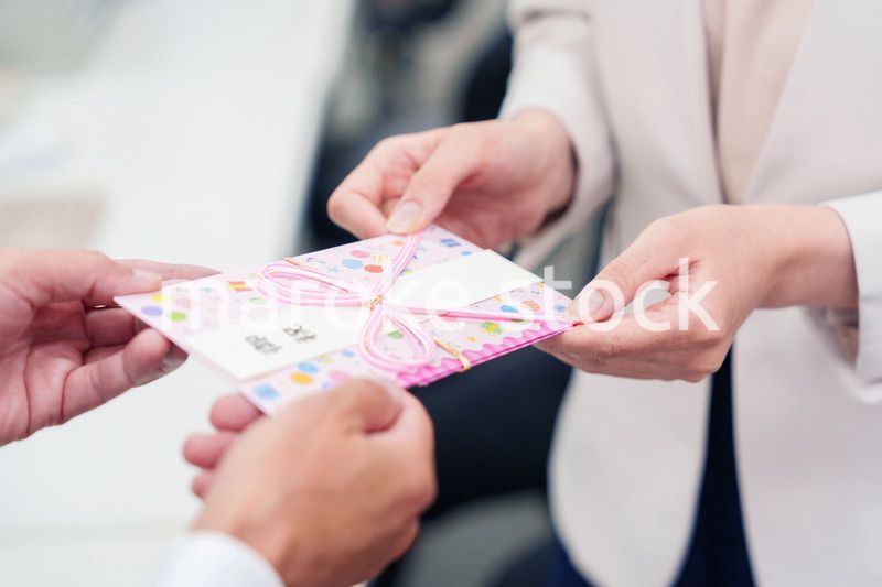 上司からお祝いを手渡されるビジネスウーマン