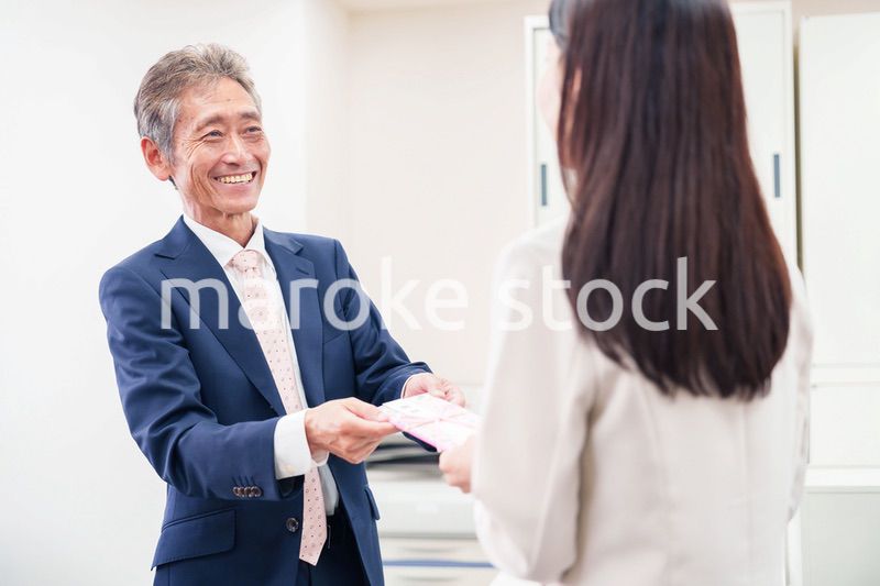上司からお祝いを手渡されるビジネスウーマン