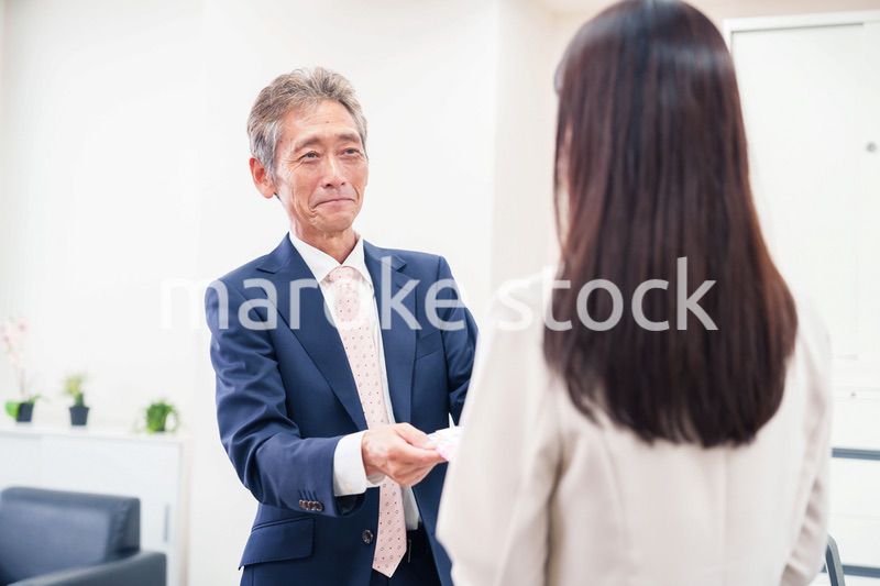 上司からお祝いを手渡されるビジネスウーマン