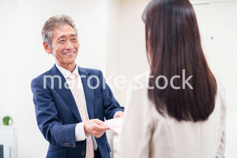 上司からお祝いを手渡されるビジネスウーマン