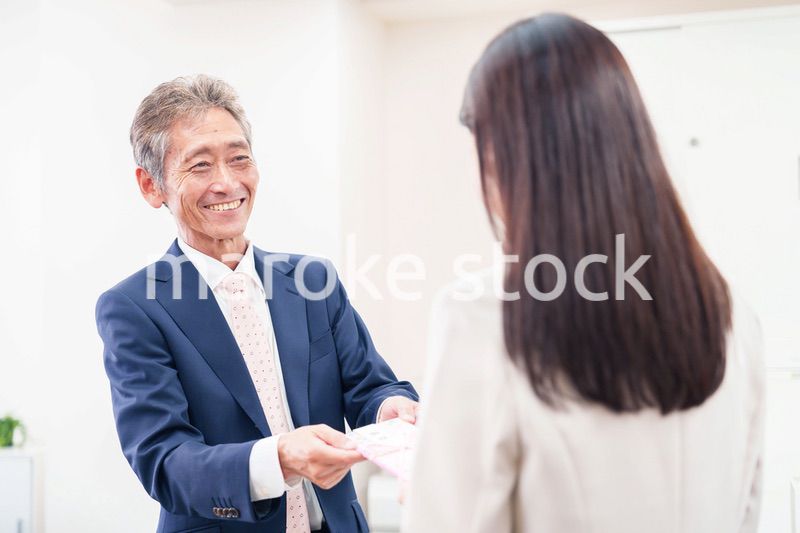 上司からお祝いを手渡されるビジネスウーマン