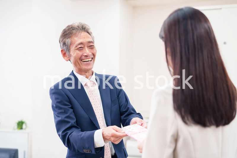 上司からお祝いを手渡されるビジネスウーマン