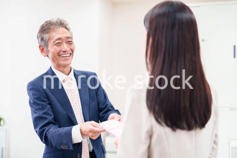 上司からお祝いを手渡されるビジネスウーマン